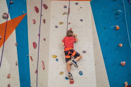 Boy at the climbing wall without a helmet, danger at the climbing wall.