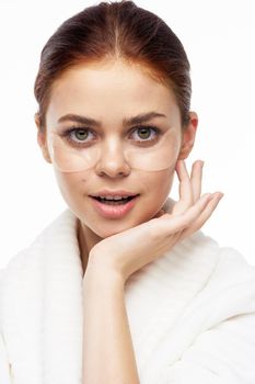 Woman in white robe posing fun skin care patches on face. High quality photo