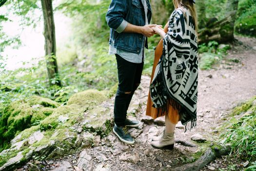 Man holding hands of a pregnant woman on a path in the park. High quality photo