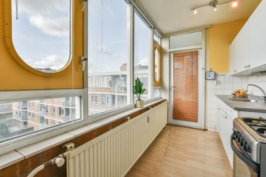 Long modern kitchen in front of a long large window with beautiful parquet flooring