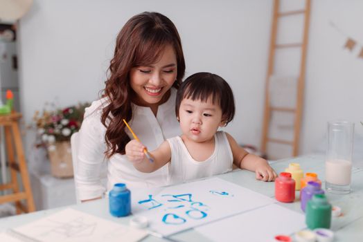 Young mother looking how her daughter drawing a picture
