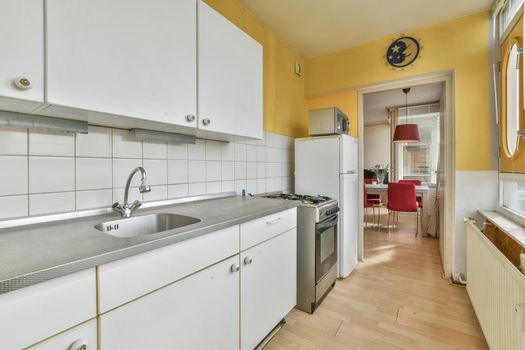 Long modern kitchen in front of a long large window with beautiful parquet flooring