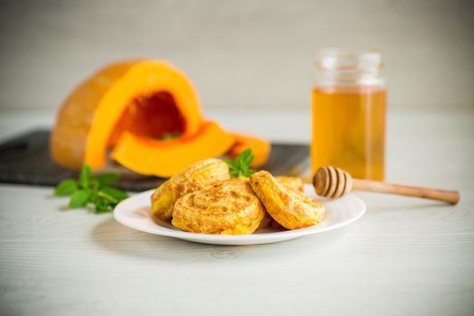 sweet lush pumpkin pancakes with honey in a plate on a wooden table