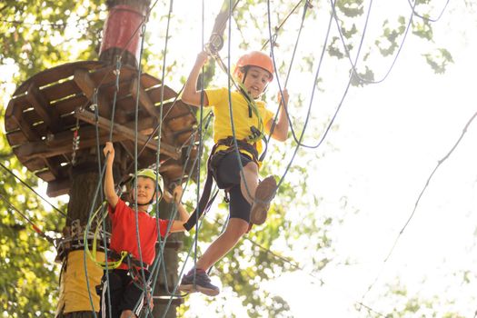 Cute children. Boy and girl climbing in a rope playground structure at adventure park.