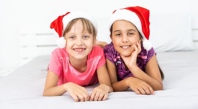 Two Children wearing Santa hats smiling on isolated white background.