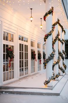 Christmas porch.Snowy courtyard with Christmas porch, veranda, wreath, Christmas tree, garland,christmas balls and lanterns.