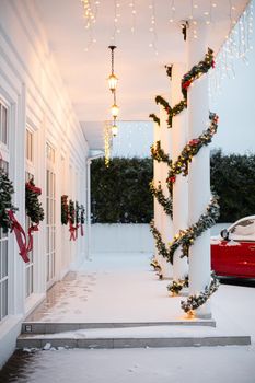 Christmas porch.Snowy courtyard with Christmas porch, veranda, wreath, Christmas tree, garland,christmas balls and lanterns.