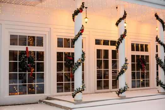 Christmas porch.Snowy courtyard with Christmas porch, veranda, wreath, Christmas tree, garland,christmas balls and lanterns.