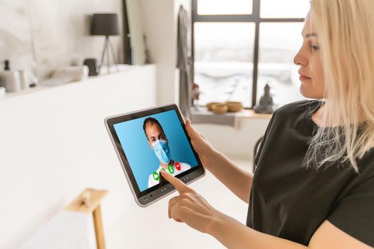 Woman talking with a doctor online using digital tablet, feeling bad at home. Concept of telemedicine and patient counseling online.