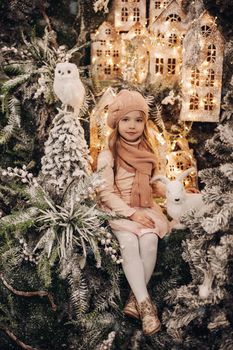 beautiful girl in a christmas decoration with a lot of trees under a snow and lights on background