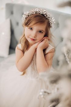 young caucasian girl with long fair hair and pretty face in white dress poses for the camera