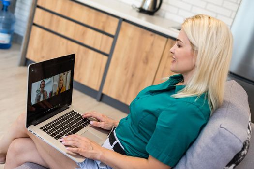 Cropped image of young woman using laptop for video conference at home.