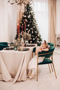 attractive caucasian girl in beautiful dress in the kitchen near the christmas tree and smiles