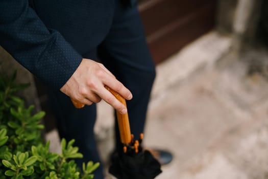 Man hand rests on the wooden cane of the umbrella. Close-up. High quality photo