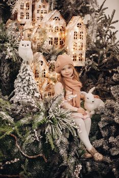 beautiful girl takes photos in a christmas decoration with a lot of trees under a snow and lights on background