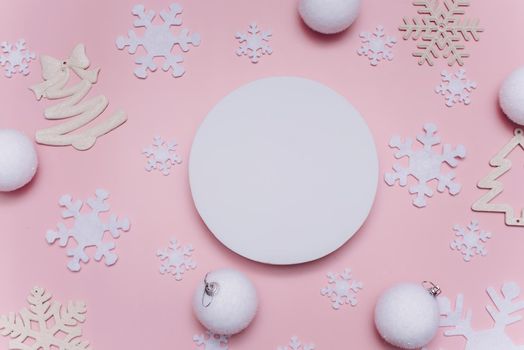 White circle with place for text on a pink background with snowflakes and Christmas decorations. Mock up, copy space.