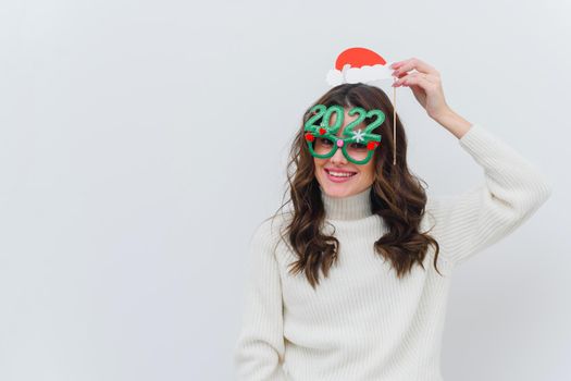 Woman in white sweater wearing santa hat and glasses 2022 on white isolated background.