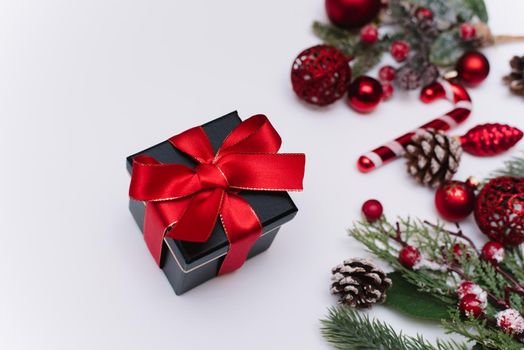 Christmas gift box on a white table with fir branches and red decorations. Flat lay with copy space.