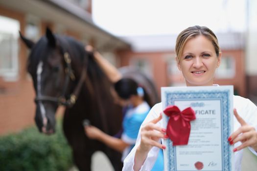 Woman doctor shows horse veterinary certificate, close-up, blurry. Equestrian sports tourism, competitions