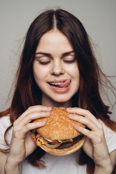 woman with a hamburger in her hands a snack fast food close-up. High quality photo