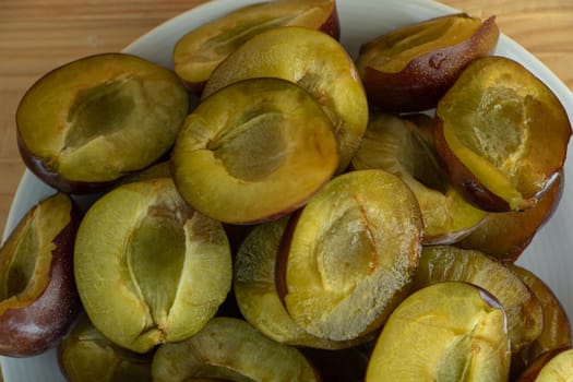 Sliced tasty juicy plums on a plate close up, plums benefits concept.