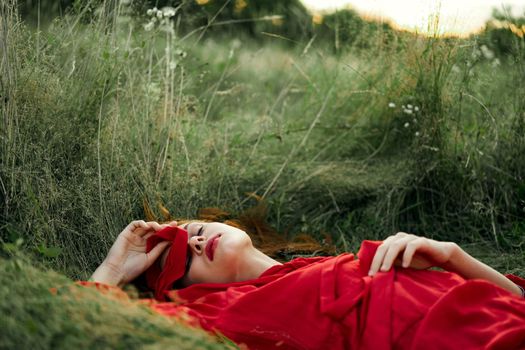 woman in red dress lying on the grass fresh air nature romance. High quality photo