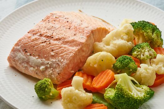 Steam salmon and vegetables, Paleo, keto, fodmap, dash diet. Mediterranean diet with steamed vegetables and fish. Healthy concept, white plate on a gray table, gluten free, lectine free, macro