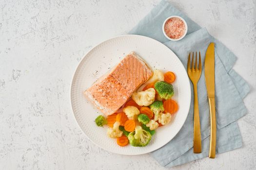 Steam salmon and vegetables, Paleo, keto, fodmap, dash diet. Mediterranean diet with steamed vegetables and fish. Healthy concept, white plate on a gray table, gluten free, lectine free, top view
