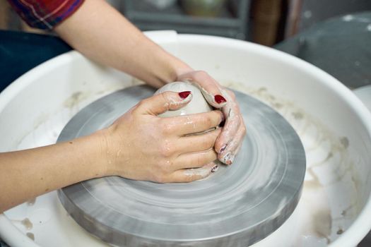 Woman making ceramic pottery on wheel, hands closeup. Concept for woman in freelance, business, creative hobby. Earn extra money, side hustle