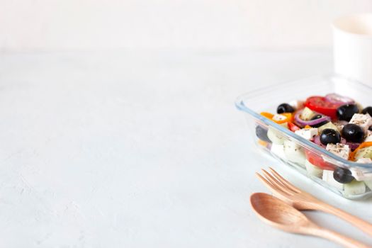 lunch box with greek salad, reusable glass container, wooden cutlery, on white background, copy space