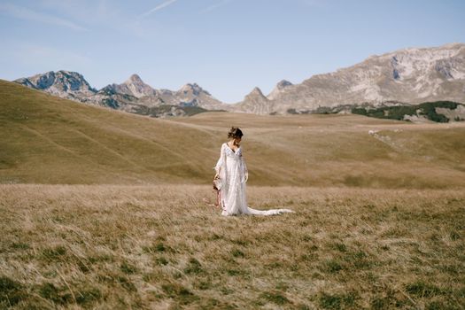 Girl in a white dress with a tambourine in her hands stands in a field. High quality photo