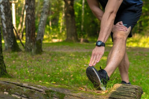 A young enduring athletic athlete is doing stretching in the forest outdoors, around the forest, oak trees.healthy nature, workout outdoor athletic wellness marathon, trees outside. Summer spring, distance stretches