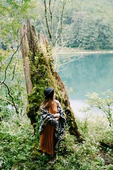 Woman stand near a tree overgrown with moss by the lake. High quality photo