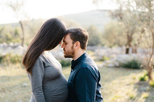 Man leaned his forehead against the forehead of pregnant woman. Portrait. High quality photo