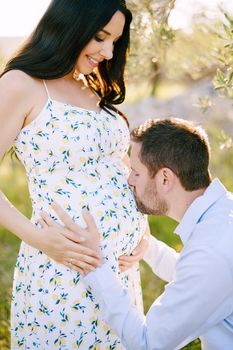 Man kissing the tummy of a pregnant woman in the park. High quality photo