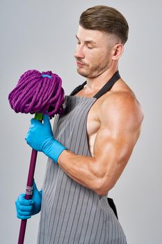 man in apron with mop in hand posing housework. High quality photo