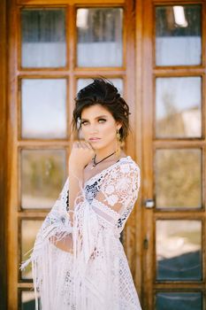 Young woman in lace dress stands near glass door. Portrait. High quality photo