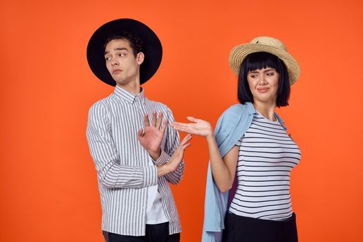 man and woman in hats posing fashion orange background. High quality photo