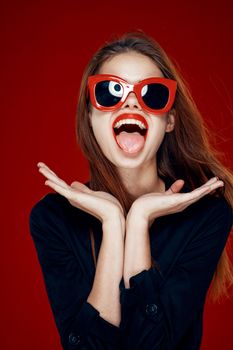 pretty woman wearing sunglasses fashion posing hairstyle red background. High quality photo
