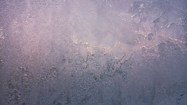 Frost and sun background. Frost texture on the window glass in winter. Ice Crystals in Winter Blue and Pink.