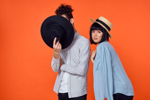 man and woman in hats posing fashion orange background. High quality photo