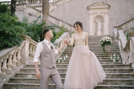 Groom helps bride down the stone steps. High quality photo