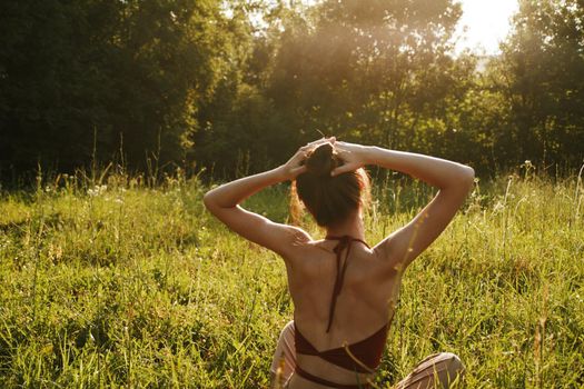 woman in summer sitting on the grass outdoors meditation freedom. High quality photo