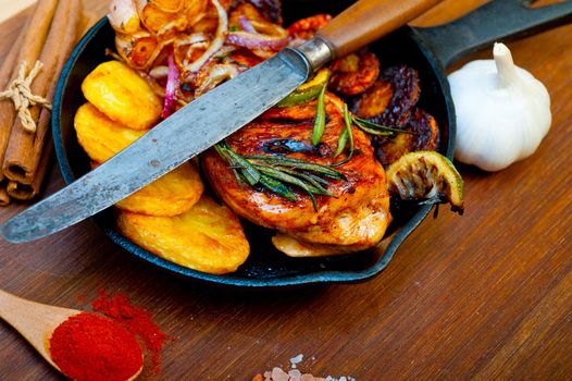 roasted grilled BBQ chicken breast with herbs and spices rustic style on iron skillet