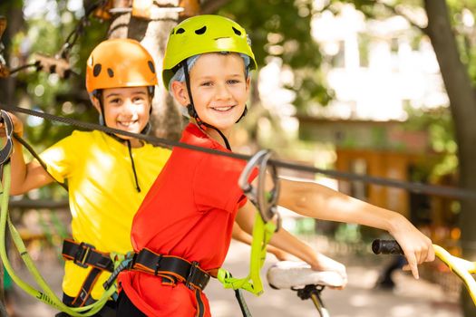 Child in forest adventure park. Kids climb on high rope trail. Agility and climbing outdoor amusement center for children. Little girl playing outdoors. School yard playground with rope way