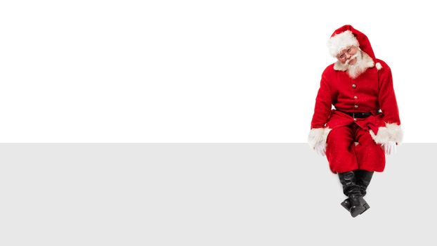 Santa Claus sitting on a blank panel isolated on white background