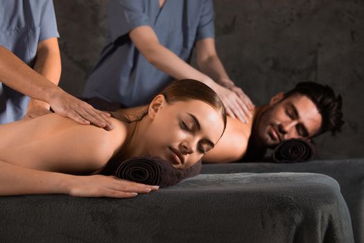Couple having spa massage oil Ayurveda treatment. Couple lying on dark towels