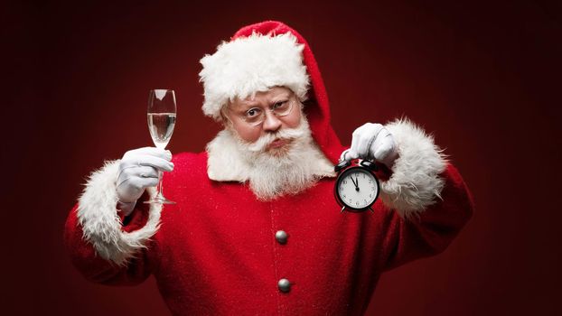 Santa claus with alarm clock almost midnight and champagne