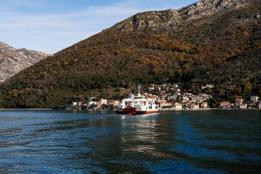 Large ship sails to a town on the coast of the sea at the foot of the mountains. High quality photo