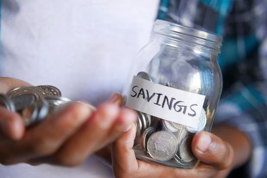 young man hand hold saving coins jar .